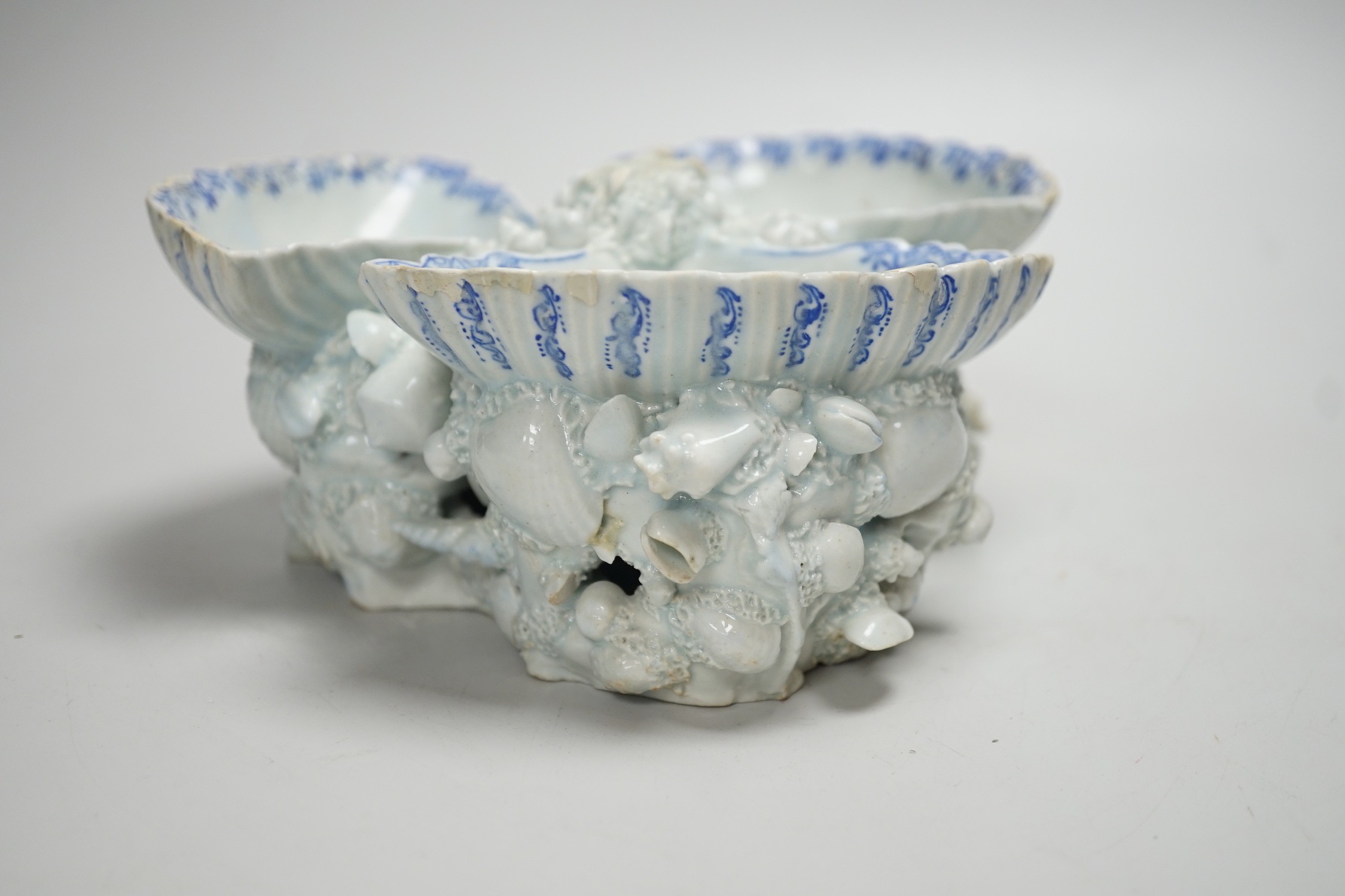 An early Bow porcelain three shell salt, the naturalistically modelled shells picked out in underglaze blue, on a shell and coral encrusted base, 8cm high